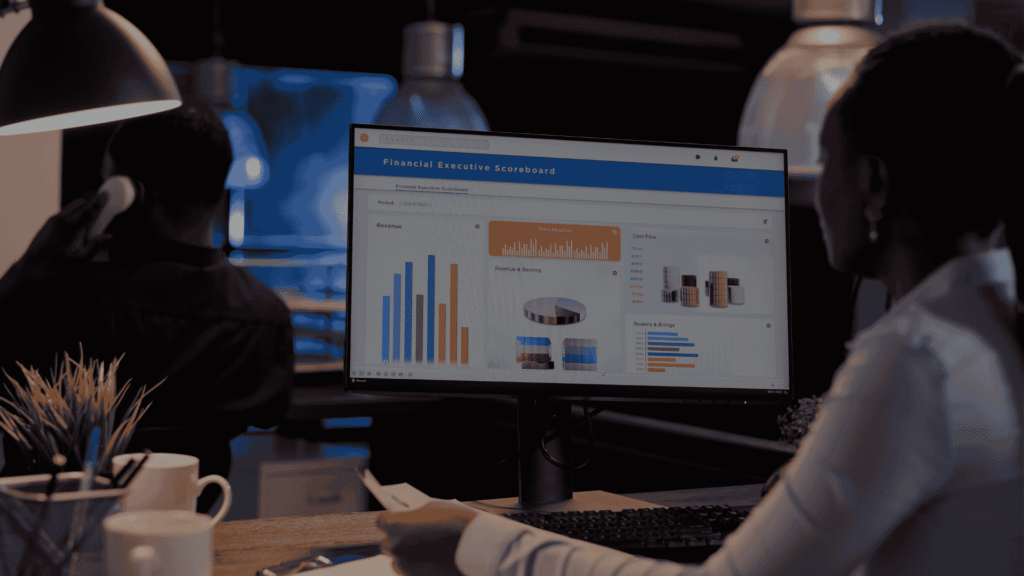 Professional workspace with a person reviewing financial dashboards on a computer monitor.