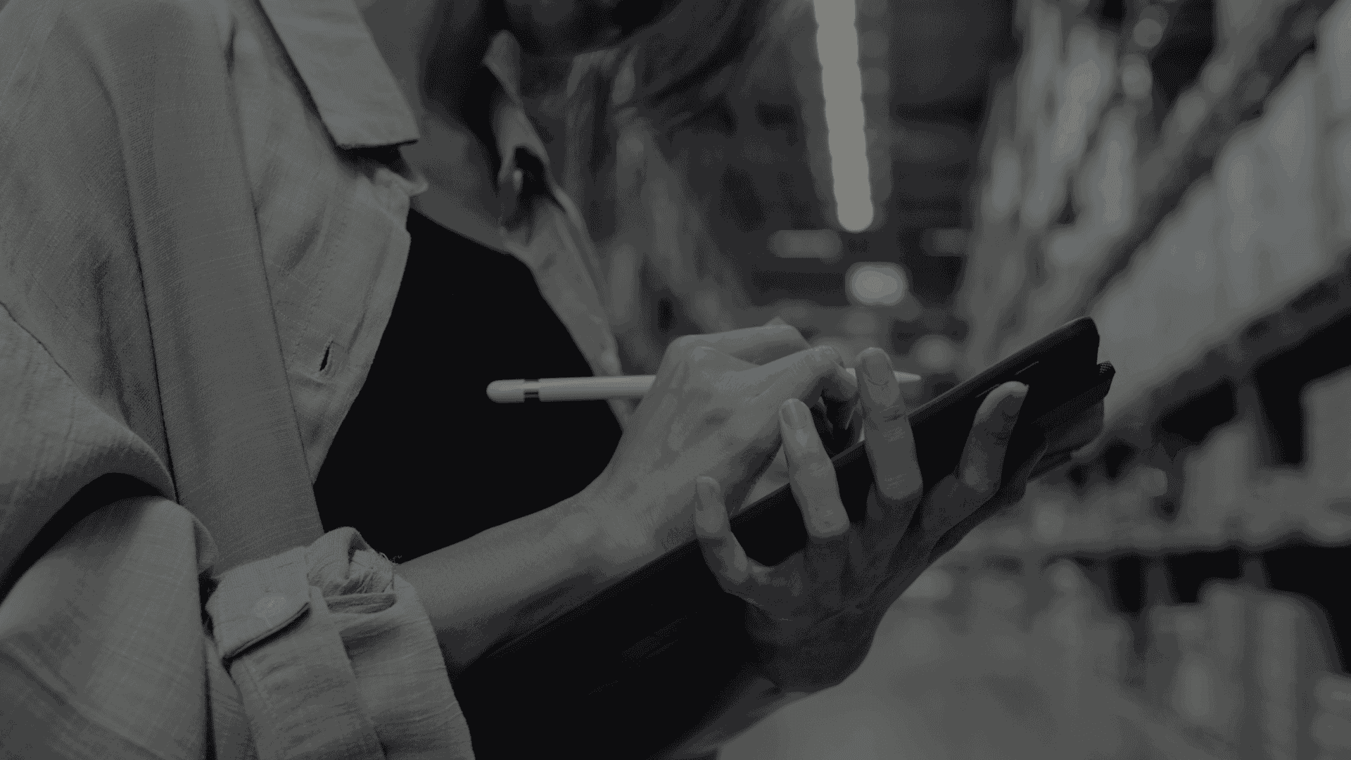a person holding a tablet and stylus while inspecting items in a warehouse aisle.