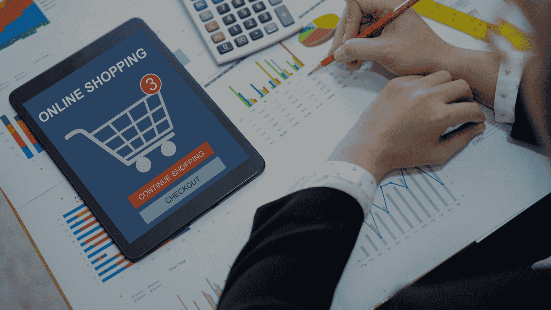 Accountant analyzing online shopping sales data with charts and calculator on desk
