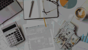 Flat-lay of a form surrounded by a calculator, laptop, glasses, notebook, coffee, cash, and financial charts.