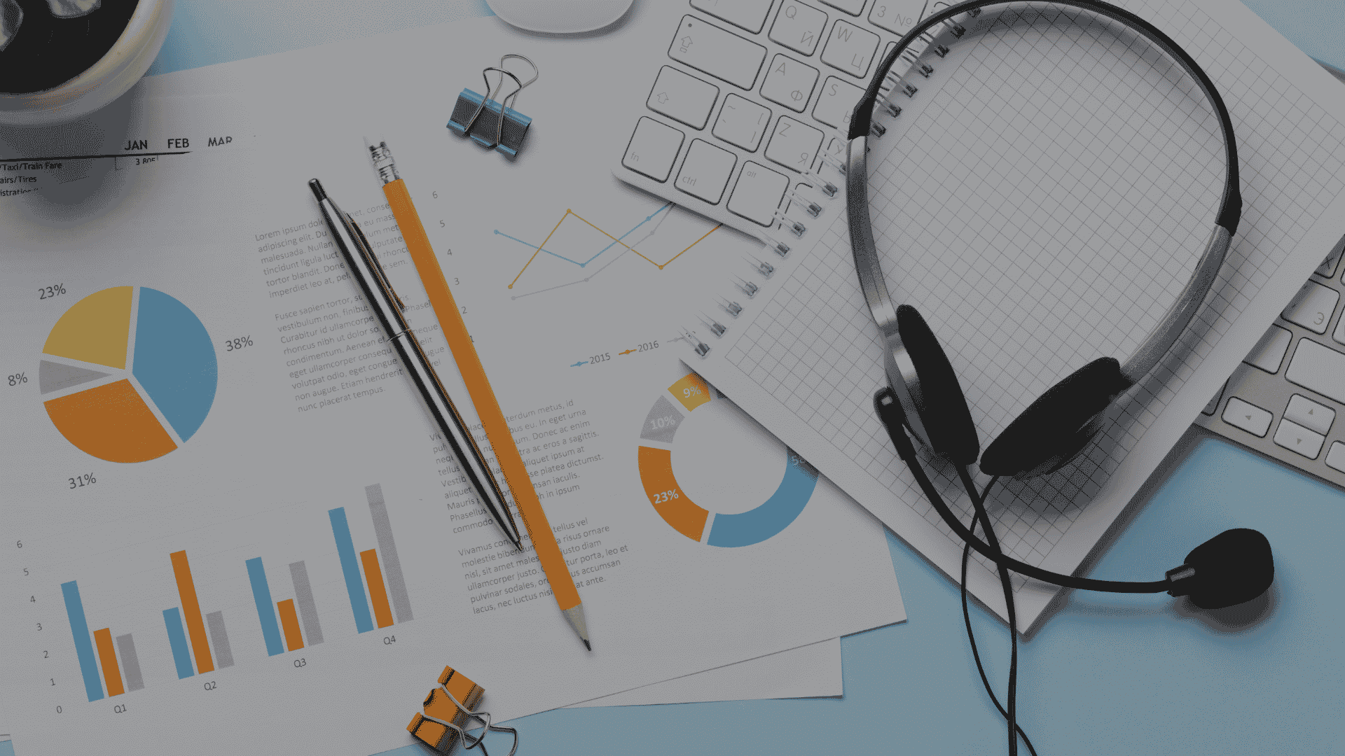 Flat-lay of a desk with a customer support headset, keyboard, printed charts, and stationery on a light blue background.