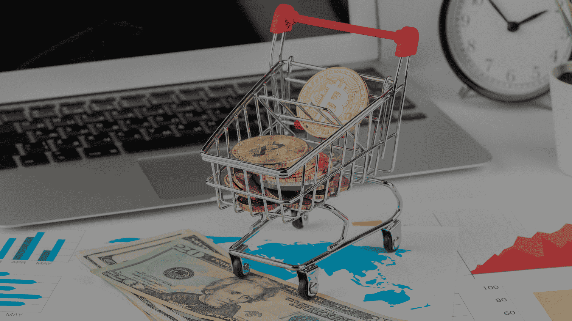 Miniature shopping cart filled with cryptocurrency coins sits on financial charts
